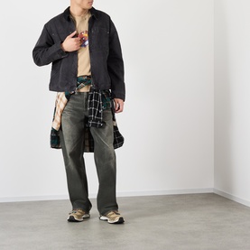 Model wearing Vans beige cotton T-shirt, styled with dark jacket, khaki trousers, plaid shirt tied at waist and chunky trainers.