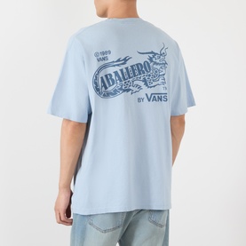 Model wearing Vans Caballero light blue cotton T-shirt, shown from behind with dragon graphic print, styled with light wash jeans.
