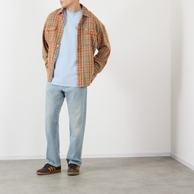 Model wearing VANS light blue cotton T-shirt, styled with tan plaid overshirt and light wash jeans.