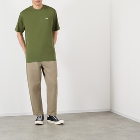 Model wearing Vans green cotton T-shirt with chest logo, styled with beige chinos and black high-top trainers.