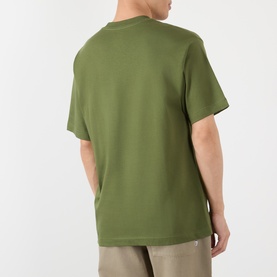 Model wearing Vans green cotton T-shirt, rear view, with beige trousers