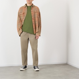 Model wearing Vans green cotton T-shirt, styled with orange check overshirt, taupe trousers and black high-top trainers.