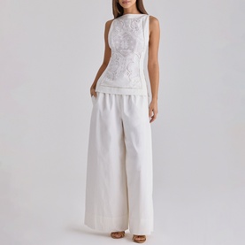 Model wearing House of CB white sleeveless embroidered top styled with wide-leg white trousers