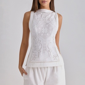 Model wearing House of CB white sleeveless top with broderie anglaise detail, styled with white wide-leg trousers