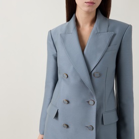 Model wearing a light blue double-breasted blazer with structured shoulders and tonal buttons, cropped close-up view