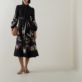Model wearing Zimmermann Black Bouquet linen dress with balloon sleeves, button front, belted waist, and floral hem, styled with a tan bag and mule