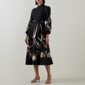 Model wearing Zimmermann Black Bouquet linen midi dress with floral hem, puff sleeves, button placket and tie belt, styled with nude heeled mules.