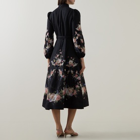Model wearing Zimmermann Black Bouquet linen dress, back view, featuring floral print, puff sleeves, belted waist and midi length.