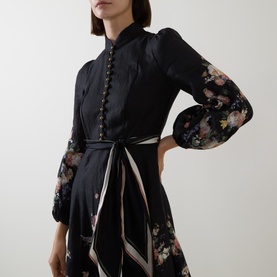 Model wearing Zimmermann Black Bouquet linen dress with floral print sleeves, button front detail, and tie waist belt.