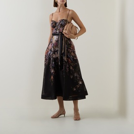 Model wearing Zimmermann Black Floral linen-silk dress with corset bodice and full midi skirt, styled with nude heels and a small bag.
