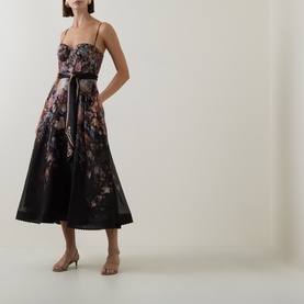 Model wearing Zimmermann Black Floral linen-silk midi dress with bustier bodice, full skirt, ribbon belt, and spaghetti straps.