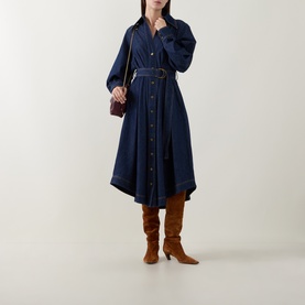 Model wearing Zimmermann Belted Denim Shirt Dress in Harbour Blue with brown knee-high boots and small burgundy crossbody bag.