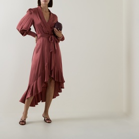 Model wearing Zimmermann Blush Rose silk wrap dress with ruffle hem and tie waist, styled with strappy heels and clutch bag.