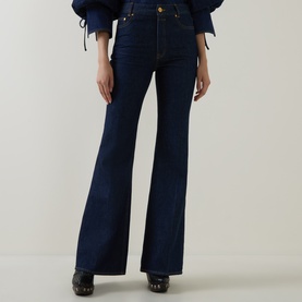 Model wearing Zimmermann Harbour Blue high-rise flare jeans in dark denim, styled with a blue blouse and dark heeled clogs.