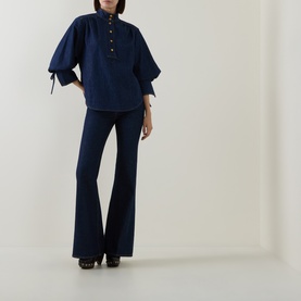 Model wearing Zimmermann Harbour Blue flare jeans, styled with matching navy blouse and black heels