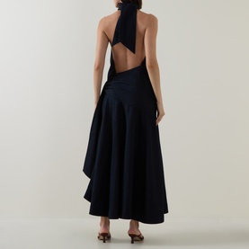 Model wearing Zimmermann dress in Night Sky, backless halterneck design with bow tie detail and asymmetric flared midi skirt in cotton