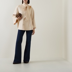 Model wearing Zimmermann cream wool-blend jacket with bow neckline and flared sleeves, styled with navy flare trousers and brown clutch.