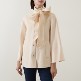 Model wearing Zimmermann cream wool jacket with bow neck tie, flared sleeves, and front button fastening, styled with navy trousers.
