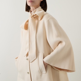 Model wearing Zimmermann cream wool-blend jacket with wide sleeves, snap fastening, and matching scarf tied at neck