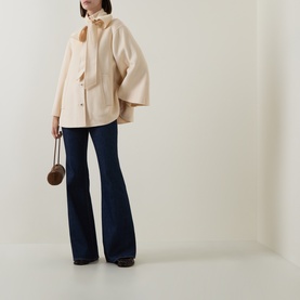 Model wearing Zimmermann cream wool blend jacket with wide sleeves, styled with dark flare jeans, carrying a small round brown bag.