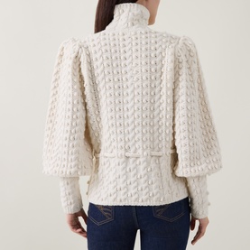 Model wearing Zimmermann Bubble Textured Turtleneck Sweater in cream, showing puff shoulders, blouson sleeves, and bubble-knit texture. Styled with