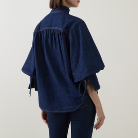 Model wearing Zimmermann Harbour Blue denim shirt with wide kimono sleeves, tie cuffs and gather detail at back yoke, styled with dark jeans