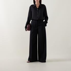 Model wearing Zimmermann Valiant Silk Shirt in black with classic collar, long sleeves, styled with wide-leg trousers and burgundy clutch bag.