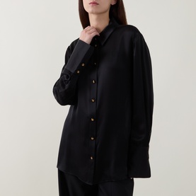 Model wearing Zimmermann Valiant Silk Shirt in black with classic collar, gold statement buttons, long sleeves, and flared cuffs, styled with black