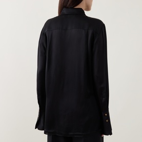 Model wearing Zimmermann Valiant Silk Shirt in black, rear view showing classic collar, long sleeves with flared cuffs and curved hem.