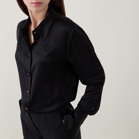 Model wearing Zimmermann Valiant Silk Shirt in black with classic collar, gold-tone buttons, and long sleeves with flared cuffs, styled with black