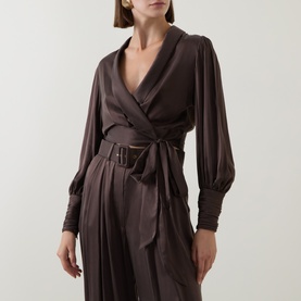 Model wearing Zimmermann Bitter Chocolate silk wrap top with deep V-neck, bishop sleeves, and belted waist, styled with matching wide-leg trousers.