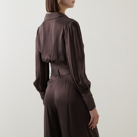 Model wearing Zimmermann Bitter Chocolate silk top with blouson sleeves and cuffed wrists, styled with matching wide-leg trousers.