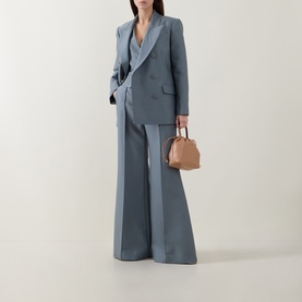 Model wearing Zimmermann Valiant Structured Flared Leg Trousers in Airforce, styled with matching blazer, carrying a tan mini bag.