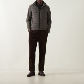 Model wearing Bugatti Dynamic Padded Jacket in olive with quilted panels, stand collar, and hood, styled with dark trousers and leather shoes
