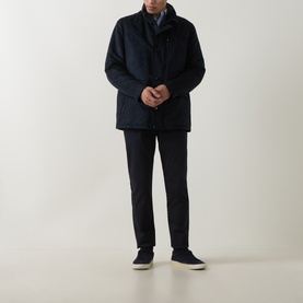 Model wearing navy quilted jacket with stand collar, styled with dark trousers and navy trainers