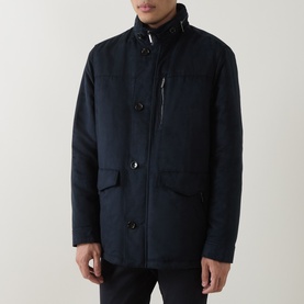 Model wearing navy wool-blend button-front coat with funnel neck, patch pockets, and zip detail