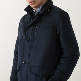 Model wearing navy padded jacket with high collar, button and zip fastening, chest pocket, styled with light blue shirt