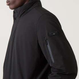 Model wearing Bugatti Rain Series Parka Jacket in black, showing stand collar, sleeve zip pocket and logo badge detail.