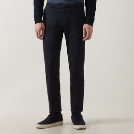 Model wearing navy slim-fit trousers styled with a navy knit top and navy suede trainers with white soles.