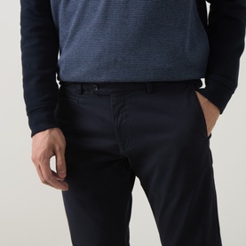 Model wearing navy slim-fit chino trousers with belt loops, styled with a navy textured knit top