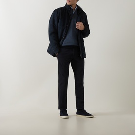 Model wearing navy shirt jacket over blue polo, styled with black trousers and navy suede trainers