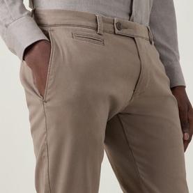Model wearing Bugatti Micro Flex Slim-Leg Chinos in beige, slim-leg fit with belt loops and rear welt pockets visible.