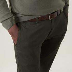 Model wearing Bugatti Micro Flex Slim-Leg Chinos in green, styled with a khaki sweatshirt and brown leather belt.