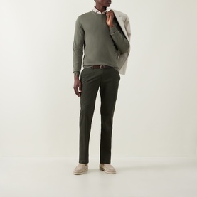 Model wearing Bugatti Micro Flex Slim-Leg Chinos in green, styled with a sage knit jumper, brown belt, and stone suede loafers.