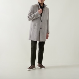 Model wearing Bugatti Logo Longline Coat in stone, stand-up collar, front button fastening, styled with dark trousers and slip-on shoes.