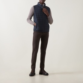 Model wearing Bugatti Air Series Padded Gilet in navy, quilted sleeveless design with funnel neck and front zip, styled with grey top and brown