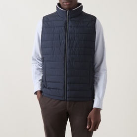 Model wearing Bugatti Air Series Padded Gilet in navy, quilted sleeveless design with funnel neck and front zip, styled with white shirt and brown