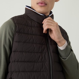 Model wearing Bugatti brown quilted polyester gilet with funnel neck zip, styled over an olive green long-sleeve top.