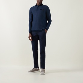 Model wearing Bugatti Textured Polo Shirt in navy blue with long sleeves and chest pocket, styled with navy trousers and grey trainers.
