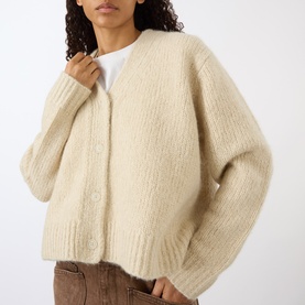 Model wearing Nili Lotan Beige Melange cardigan, chunky ribbed knit with button front, styled with white tee and brown trousers